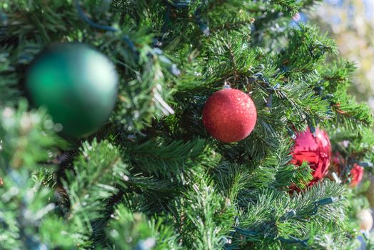 Close-up Christmas ball baubles on pine branches with two-story residential house in background