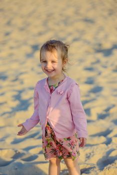 Adorable toddler girl on a sunny sand beach. Authentic childhood.