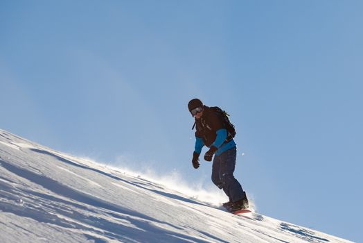 Snowboarder Riding Red Snowboard in Mountains at Sunny Day. Snowboarding and Winter Sports