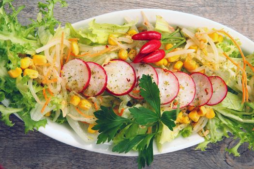 salad with radish and mais on wooden table