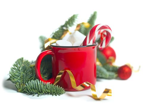 Cocoa in red mug with marshmallows and candy cane and fir tree branches and red and golden baubles and stars isolated on white background