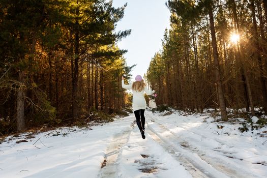 Energetic woman frolicking in the snow among the forest trees