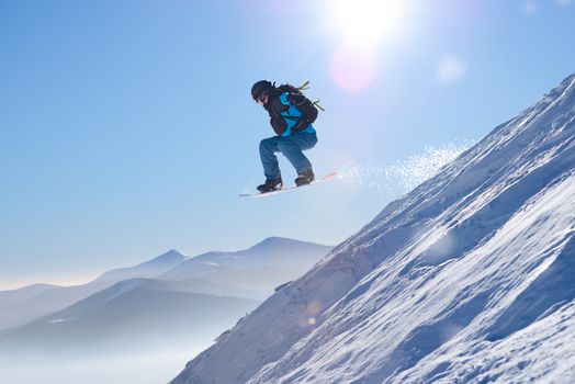 Snowboarder Jumping on Red Snowboard in Mountains at Sunny Day. Snowboarding and Winter Sports