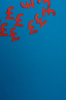 Paper yellow symbols of british pound currency on blue background. View from above with copy space