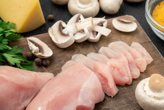 Slicing chicken breast fillet for cooking with champignons and cheese