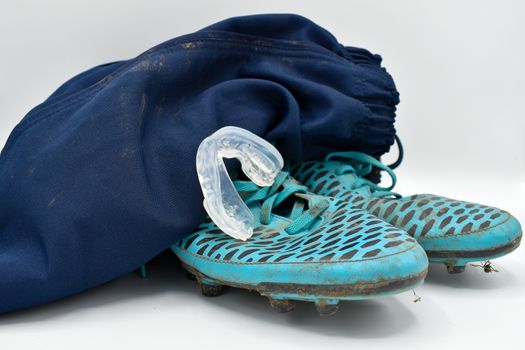 dirty rugby gear on a white background. Rugby boots, shorts and gumshield mouthguard