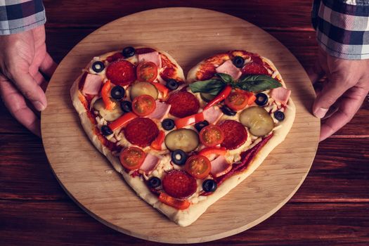 Male hands holding heart shapes pizza Valentines day surprise