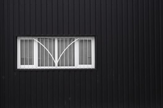 Black and white Corrugated metal sheet texture surface on a building wall with windows. Galvanize steel background.