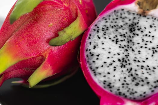 Dragon fruit. Vibrant Dragon Fruit on black background. Sliced white dragon fruit or pitaya on black plate on the table, close-up. Tropical and exotic fruits. Healthy and vitamin food concept.