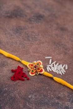 Raksha Bandhan : Rakhi with rice grains and kumkum on stone background, Traditional Indian wrist band which is a symbol of love between Brothers and Sisters.