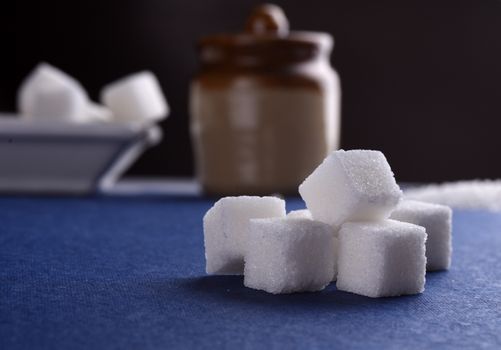 Sugar Cubes with Sugar in white plate on blue background