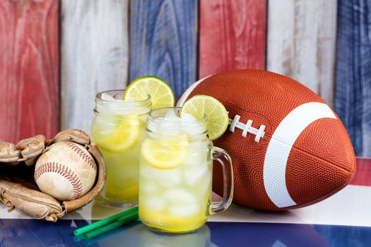 Glass jars filled with cold lemonade along with sporting objects