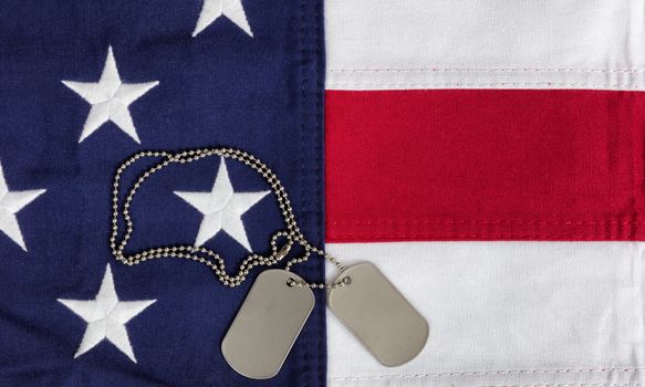Cloth United States flag with military ID tags in overhead view 