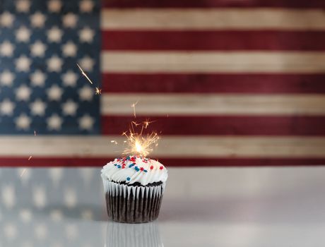 Glowing sparkler inside cupcake with rustic wooden flag of Unite