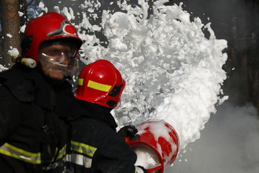Firefighter extinguishes a fire..Extinguishing the fire.  Fill the foam with a fire. Resolute firefighters.