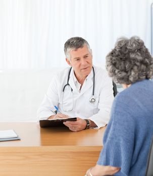 A senior doctor talking with his patient in his office