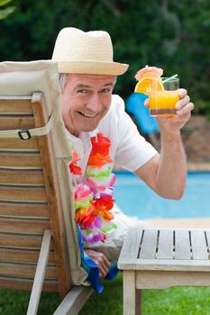 Mature man drinking a cocktail beside the swimming pool