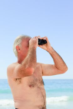 Senior man bird watching at the beach