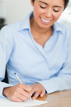 Frontal view of an attractive woman writing on a sheet of paper while sitting