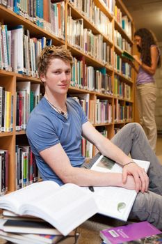 Portrait of a male student with books while his classmate is reading