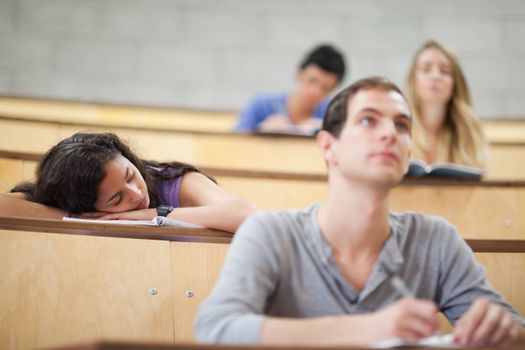 Students listening a lecturer while their classmate is sleeping
