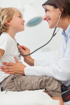 Smiling doctor auscultating a child with a stethoscope
