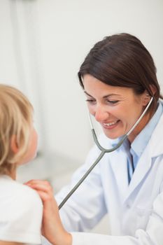 Smiling doctor auscultating a child
