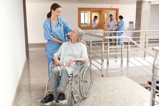 Nurse watching over old women sitting in wheelchair
