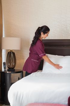Hotel maid fixing pillows