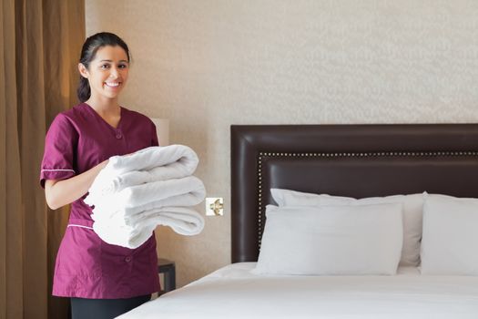 Hotel maid holding pile of fresh towels