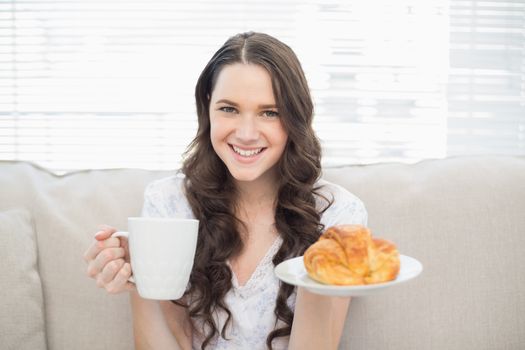 Smiling young woman in pyjamas having breakfast
