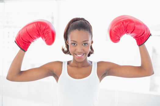 Slender athletic woman wearing boxing gloves making victorious gesture