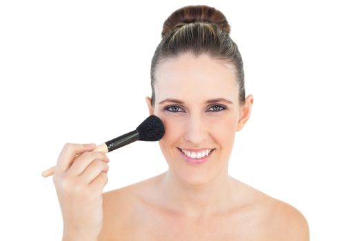Portrait of delighted woman using blusher brush