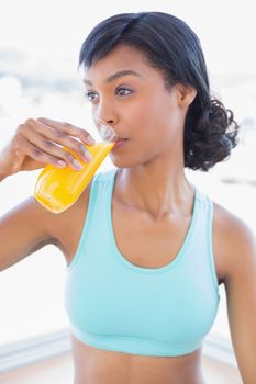 Meditative fit woman drinking a glass of orange juice