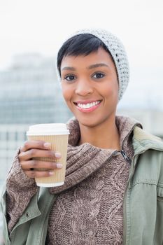 Pretty young model in winter clothes holding a coffee