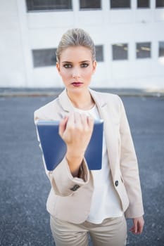 Stern stylish businesswoman holding tablet computer