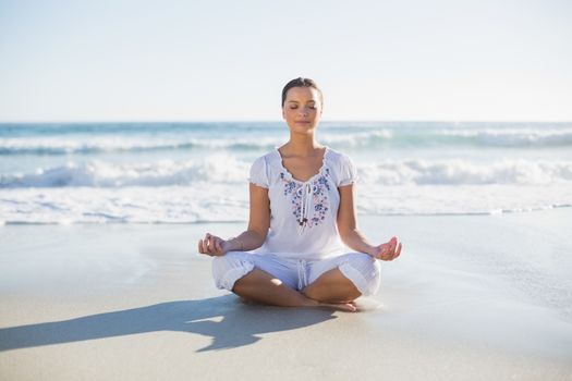 Peaceful pretty woman in lotus position on the beach