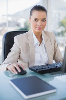 Serious businesswoman working on computer looking at camera