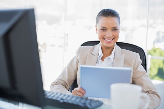 Smiling sophisticated businesswoman holding tablet pc