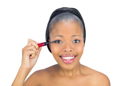 Smiling woman putting mascara on her eyelash