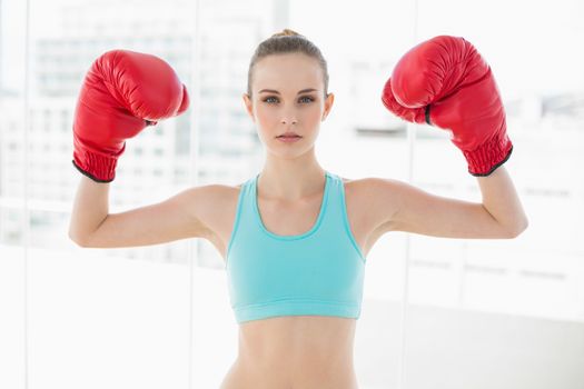 Sporty stern woman holding up boxing gloves