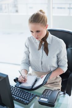 Blonde stern businesswoman writing in diary