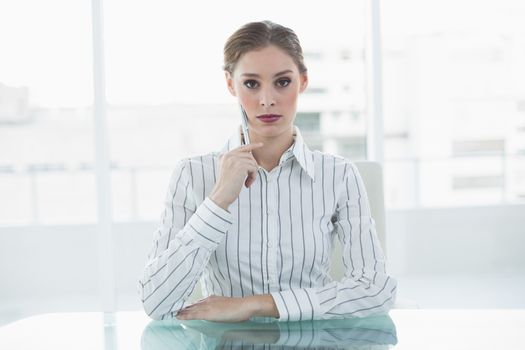 Concentrating chic businesswoman sitting thinking at her desk