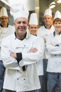 Five chefs wearing uniforms while posing in a kitchen