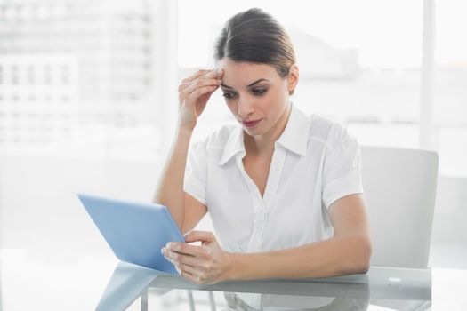 Concentrating brunette businesswoman working with her tablet 