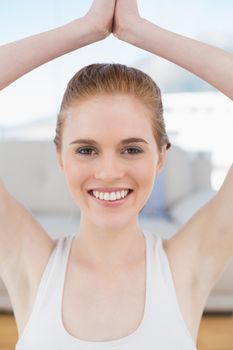 Smiling woman with joined hands over head