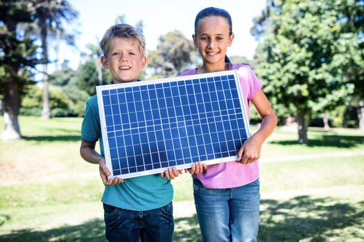 Siblings holding a solar panel