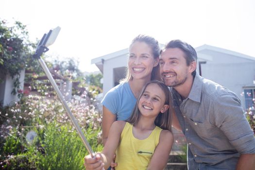 Parents and daughter taking a selfie with selfie stick
