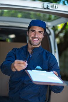 Portrait of delivery person giving clipboard for signature