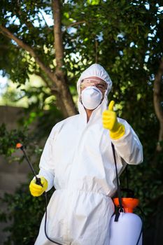 Man showing thumbs up while holding pesticide sprayer